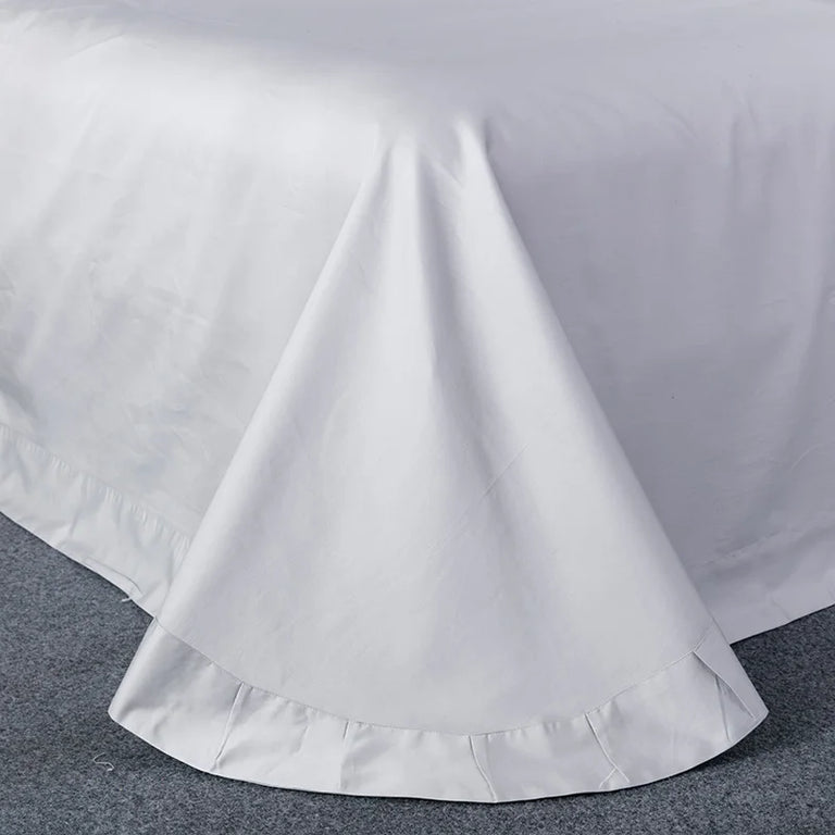 Grey flat sheet spread over a bed with a neat hem