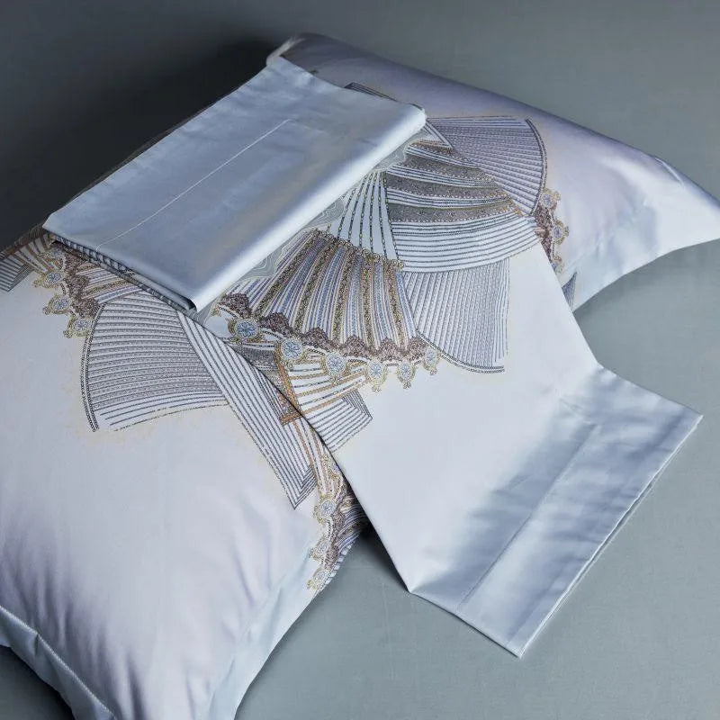 Folded silver blue sheet beside printed pillowcases