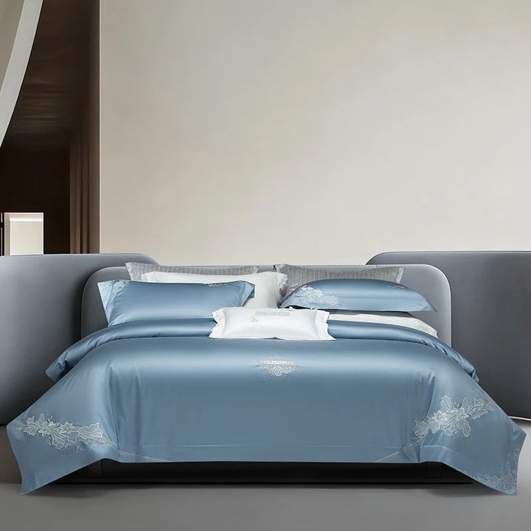 Blue Egyptian cotton bedding set with silver floral embroidery on a bed