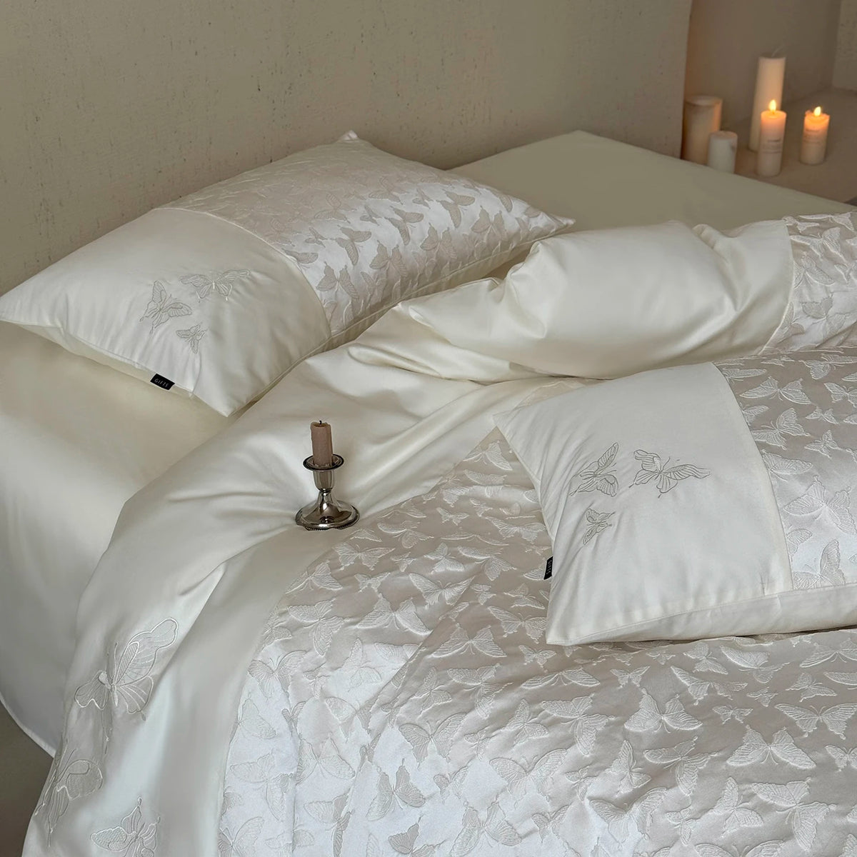 Ivory butterfly pillowcase on a bed with candles