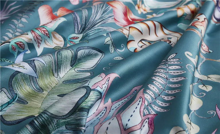 Teal tropical print fabric with leaves and pink flowers in soft folds